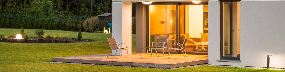 Modernes Zuhause mit Terrasse, umgeben von stimmungsvoller Außenbeleuchtung, die eine gemütliche Atmosphäre für den Außenbereich schafft.
